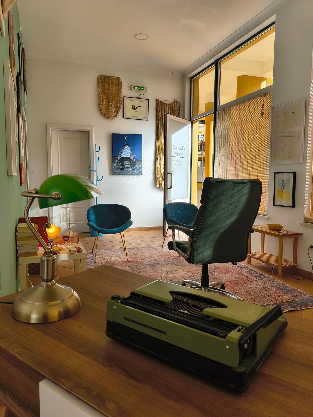 A secretária com o candeeiro verde e a máquina de escrever, com a sala de consulta ao fundo